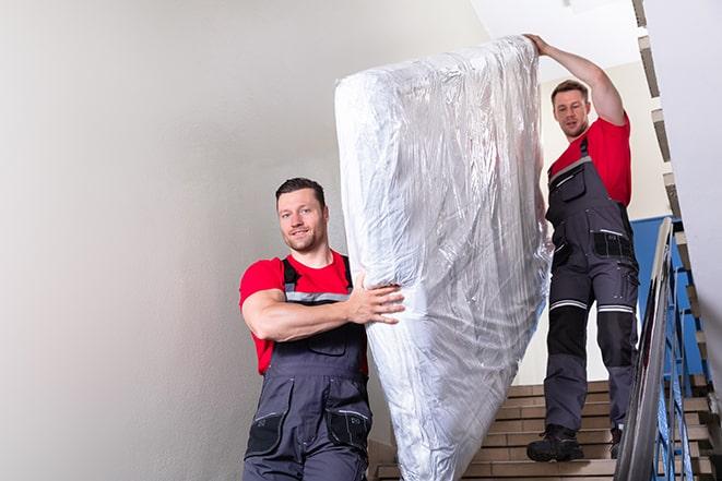 heavy lifting workers transporting a box spring out of a building in Lisbon